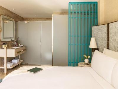 Moderní hotelový pokoj s velkou postelí, nočním stolkem a elegantním osvětlením.