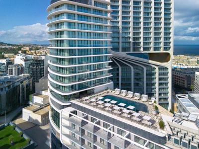 Moderner Hochhauskomplex mit abgerundeten Ecken und Terrasse mit Pool auf oberer Etage bei Tageslicht.