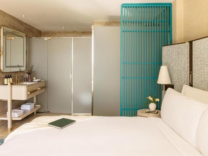 Moderní hotelový pokoj s velkou postelí, nočním stolkem a elegantním osvětlením.