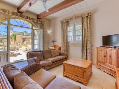 Světý obývací pokoj s hnědými pohovkami, dřevěným nábytkem a výhledem na slunnou terasu.