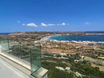 Vista de una ciudad costera con playa, mar y cielo azul desde una barandilla de vidrio.