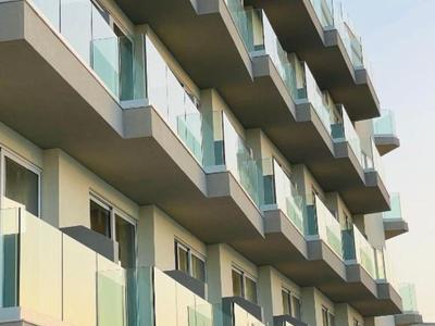 Moderner Hotelbau mit mehreren Stockwerken und Balkonen mit Glasgeländern.