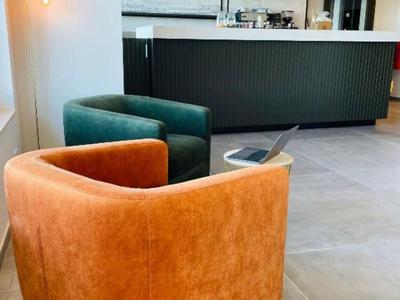 Moderne Lounge mit orangefarbenem und grünem Sessel vor einer stilvollen Bar.