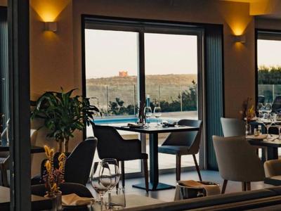 Ein stilvolles Restaurant mit Tischen und Stühlen neben großen Fenstern mit Blick auf eine Poollandschaft.