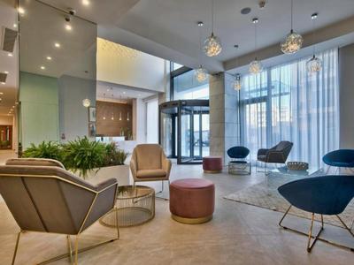 Moderne hotel lobby met stijlvolle stoelen, groen en grote ramen die natuurlijk licht binnenlaten.