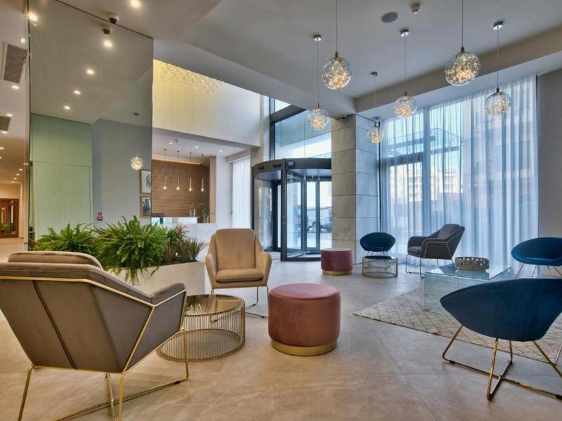 Moderne hotel lobby met stijlvolle stoelen, groen en grote ramen die natuurlijk licht binnenlaten.
