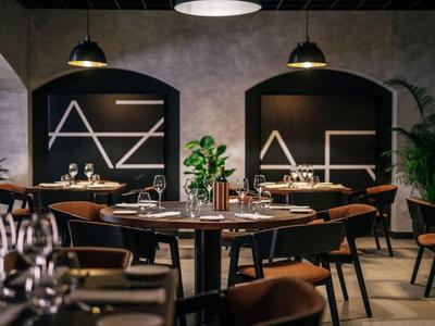 Modern restaurant met elegante houten tafels, leren stoelen en stijlvolle verlichting.