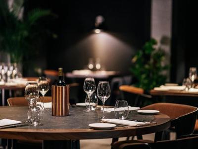 Elegantes Restaurant mit gedeckten Tischen, Weingläsern und gedämpfter Beleuchtung.