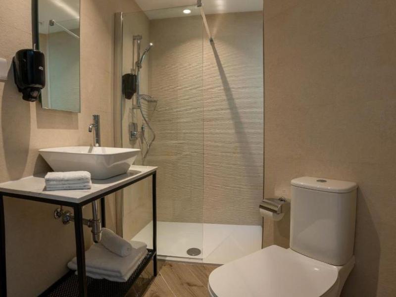 Modernes Badezimmer mit Dusche, Toilette und Waschbecken mit Spiegel und Handtüchern.