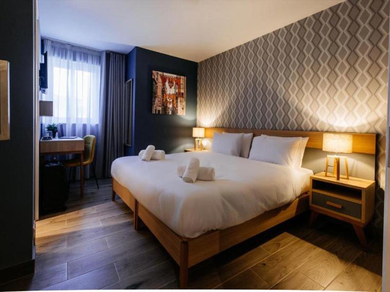 Modernes Hotelzimmer mit Doppelbett, Nachttischen und sanfter Beleuchtung.