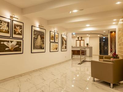 Hell erleuchteter Flur mit Marmorboden, braunem Sofa und Wänden mit gerahmten Schwarzweißbildern.