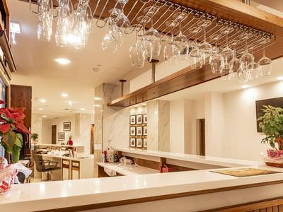 Bar d'hôtel moderne avec verres suspendus et décoration élégante sous un éclairage chaud.