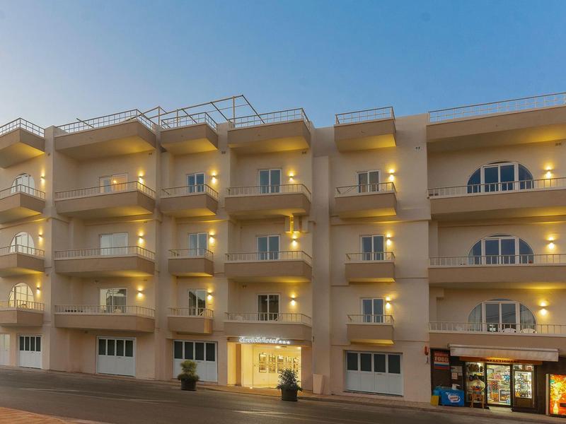 Un edificio alberghiero moderno a più piani con balconi illuminati al crepuscolo.