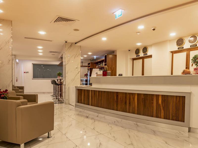 Reception di un hotel con bancone in legno e sedie moderne in un ambiente luminoso.