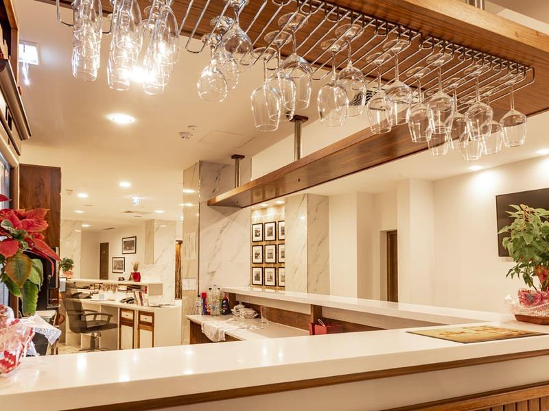 Bar dell'hotel luminosa con bicchieri da vino appesi e atmosfera accogliente.