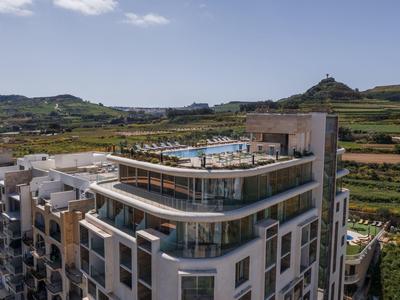 Modernes Hotelgebäude mit Dachterrasse und Pool in ländlicher Umgebung.