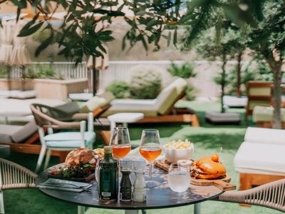 Tisch mit Getränken und Snacks vor Garten-Loungemöbeln im Freien.