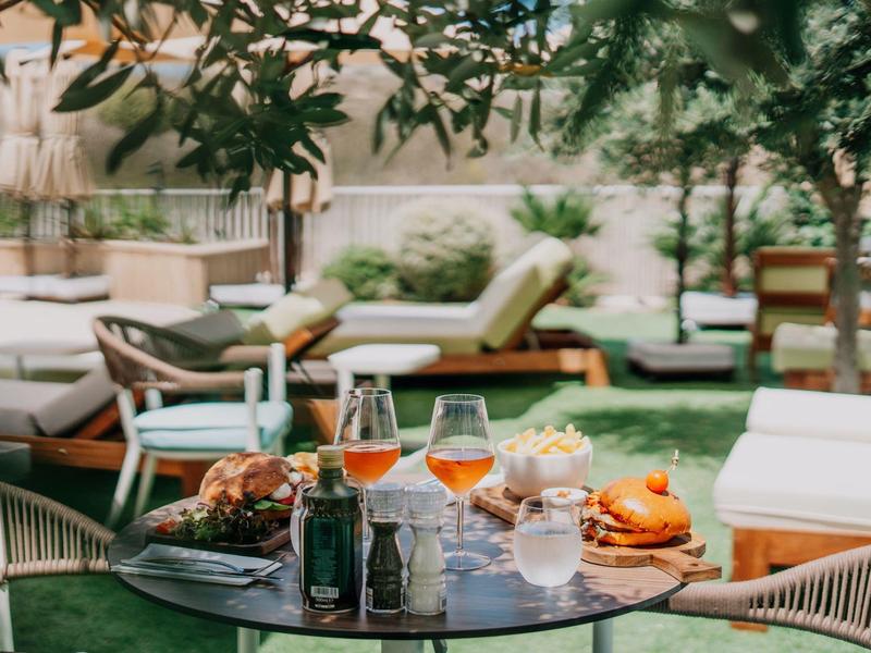 Een tuintafel met drankjes en snacks voor gezellige loungebanken.