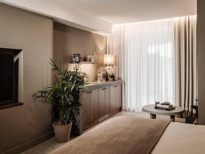 Camera d'albergo accogliente con piante decorative e illuminazione elegante.