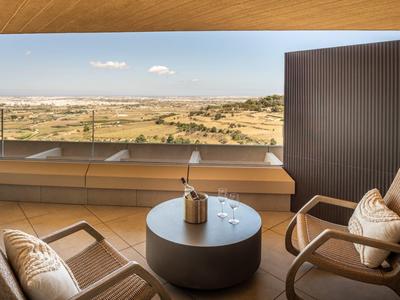 Moderner Balkon mit zwei Sesseln und Blick auf Sanddünen und Meer.