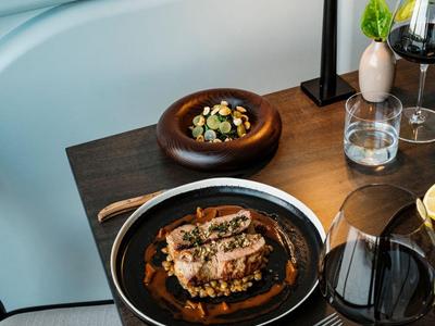 Ein elegantes Hotelzimmer-Dinner mit gebratenem Fleisch und Beilagen auf einem Holztisch.