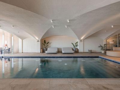 Piscine intérieure moderne avec espaces de détente et arches architecturales aux tons neutres