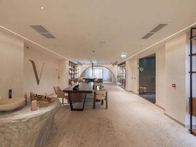 Ampia e moderna area lounge dell'hotel con mobili in pietra e legno, pareti chiare e moquette morbida.