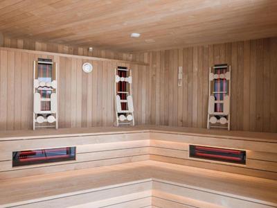 Panche e pareti in legno chiaro in una sauna finlandese moderna.