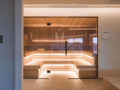 Sauna moderna con pannellature in legno e luce indiretta.