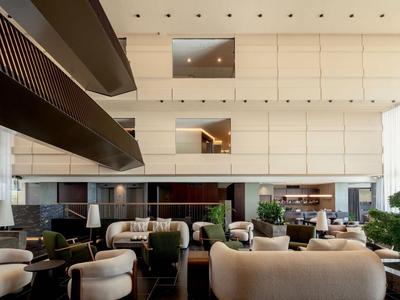 Moderner Hotel-Loungebereich mit hohen Decken, bequemen sesseln und minimalistischer Einrichtung.