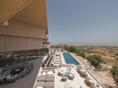Hotelterrasse mit Pool und Liegestühlen, Blick auf weite Landschaft und klaren Himmel.