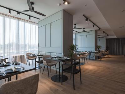 Moderner Hotelrestaurantbereich mit Holzfußboden, schwarzen Tischen, Stühlen und großen Fenstern.