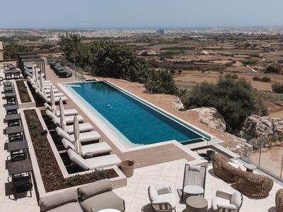 Moderner rechteckiger Swimmingpool mit weißen Liegestühlen und Aussicht auf die Landschaft.