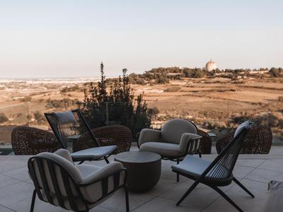 Moderne Sitzgruppe auf Terrasse mit Blick auf hügelige Landschaft bei Sonnenuntergang.