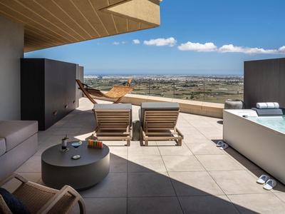 Moderne Hotelterrasse mit Lounge-Bereich, Liegestühlen und Whirlpool mit Blick auf Landschaft.