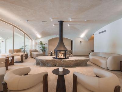 Eleganter Hotel-Loungebereich mit rundem Kamin, bequemen Ledersesseln und warmem Licht.