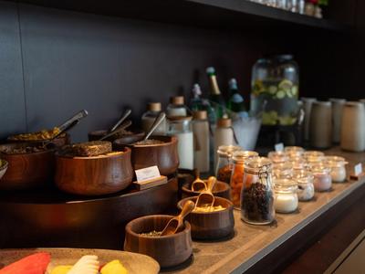 Buffet mit verschiedenen Zutaten und Gewürzen in kleinen Gläsern und Töpfen auf schwarzer Oberfläche.
