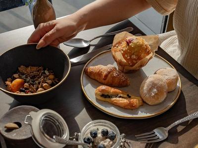 Frühstück mit Croissants, Müsli, Joghurt mit Beeren und Orangensaft auf einem Tisch.