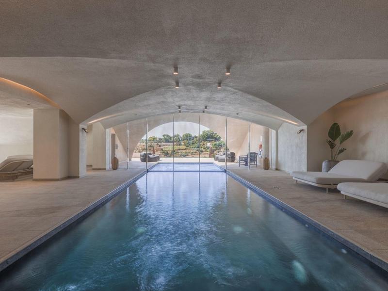 Piscina interna moderna con lettini e grandi finestre con vista sulla città.
