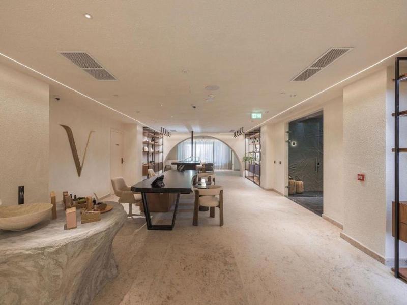 Ampia e moderna area lounge dell'hotel con mobili in pietra e legno, pareti chiare e moquette morbida.