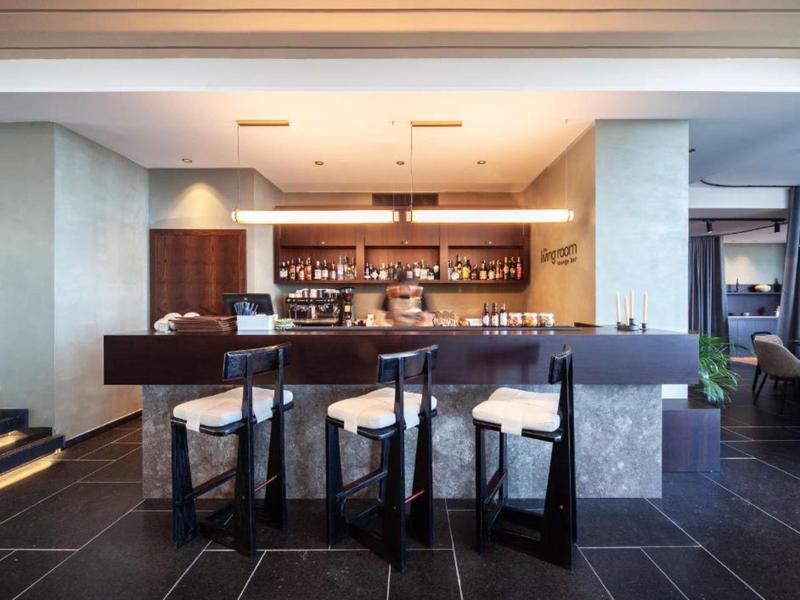 Bar dell'hotel moderno con bancone, retrobanco e tre sgabelli da bar eleganti.