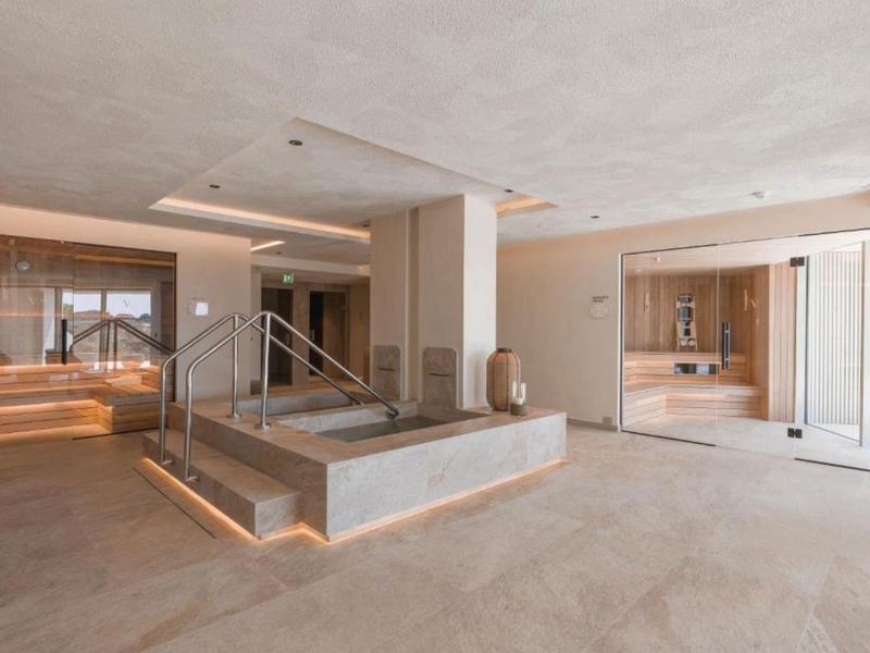 Interno di hotel luminoso e aperto con scale moderne e area salotto.