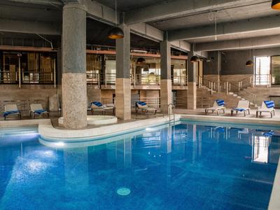 Vytápěný vnitřní bazén s lehátky a velkými sloupy v hotelu.