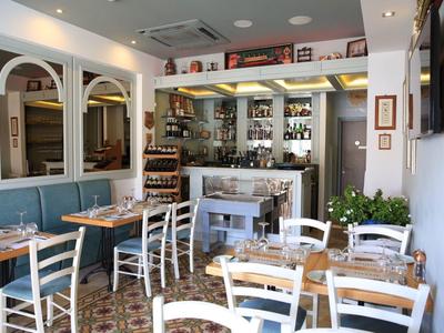 Příjemná restaurace s bílými židlemi a modrou sedací plochou, světlý a útulný interiér.