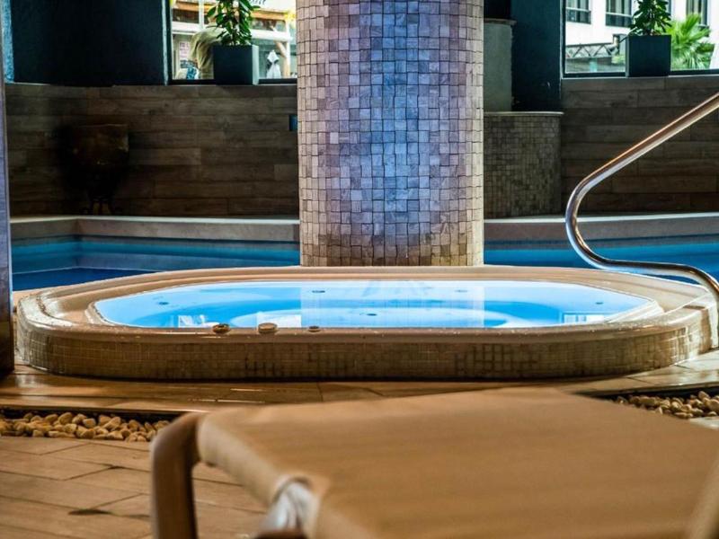 Vyhřívaná vířivka v hotelovém spa s dřevěným obložením a zábradlím