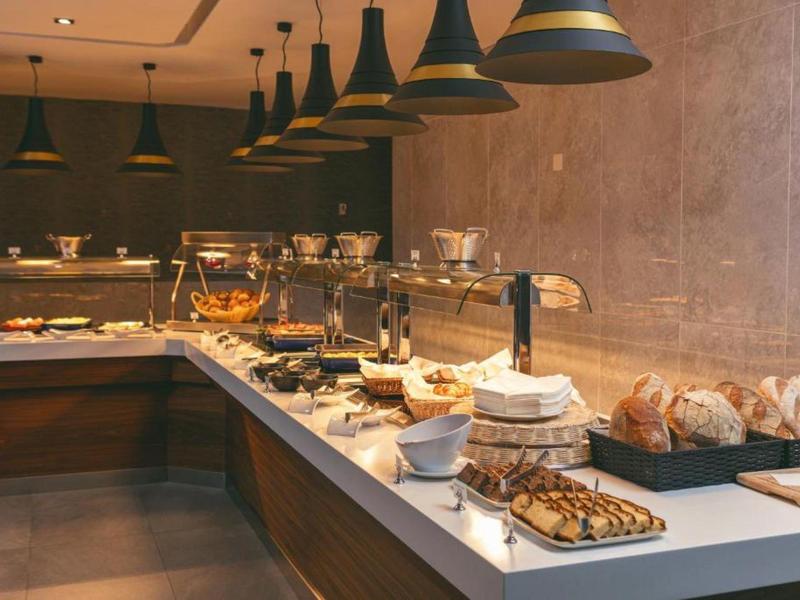 Bufet s různými jídly a pečivem v teple osvětlené hotelové restauraci.