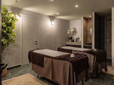 Chambre avec deux tables de soin, éclairage tamisé et plantes pour une atmosphère relaxante.