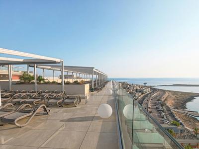 Terrasse mit Liegen und Glasgeländer mit Meerblick an einem sonnigen Tag