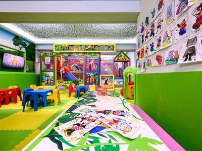 Salle de jeux colorée pour enfants avec décorations murales et jouets dans un hôtel.