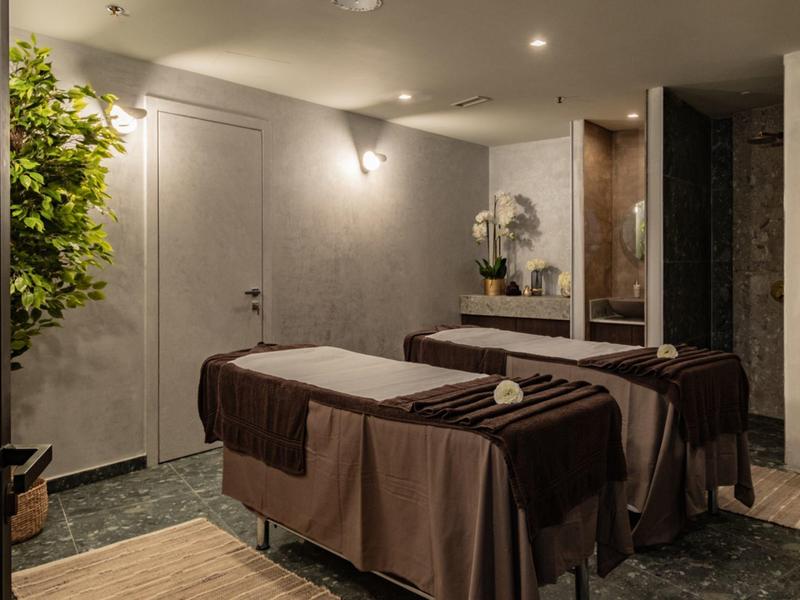 Chambre avec deux tables de soin, éclairage tamisé et plantes pour une atmosphère relaxante.